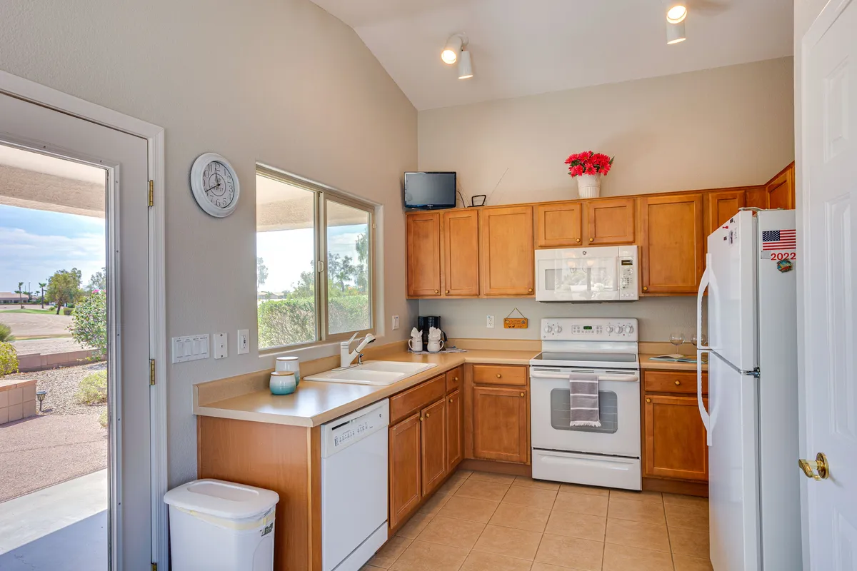 A welcoming kitchen space featuring cabinetry, modern appliances, and a window above the sink that frames a scenic view—likely the golf course referenced in the section. Natural light pours in, illuminating the warm finishes and open atmosphere ideal for both daily routines and entertaining.