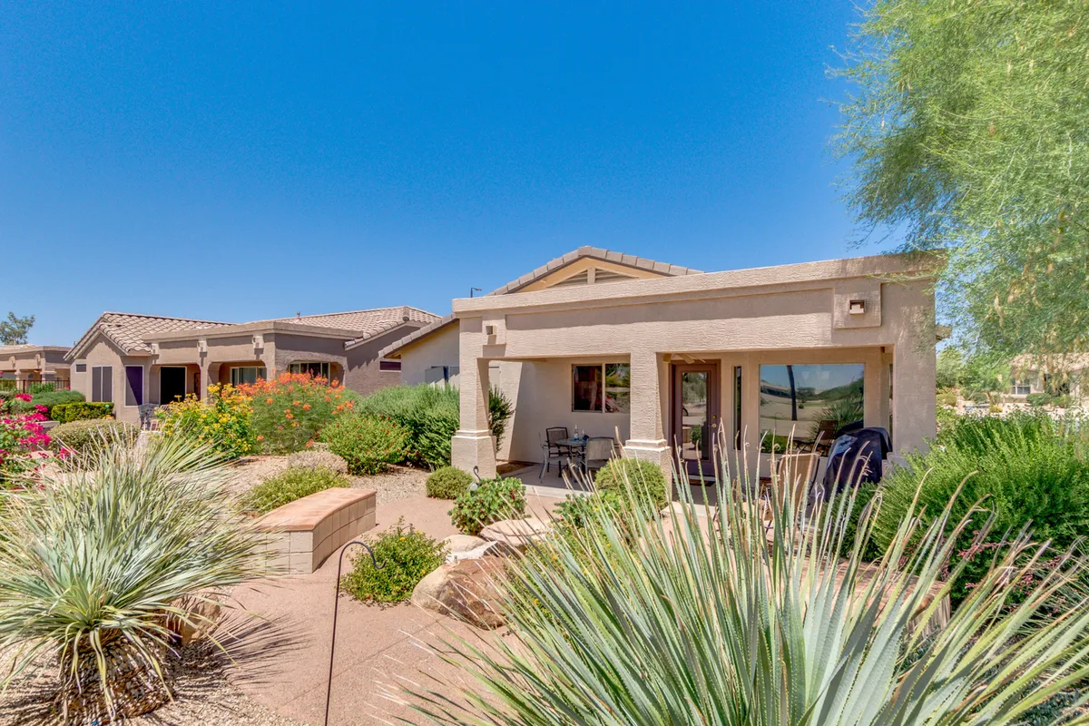 A serene look at a landscaped garden in front of the house, featuring a cozy seating area perfect for outdoor meals or relaxation. The space is bathed in warm sunlight, evoking a sense of peace and an active outdoor lifestyle.