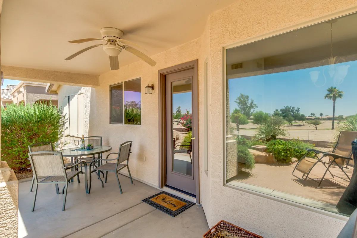 The image showcases a covered patio featuring a patio table and chairs surrounded by a landscaped garden. The scene is tranquil, perfect for outdoor dining, relaxing, or watching sunsets, with a sense of both comfort and style.